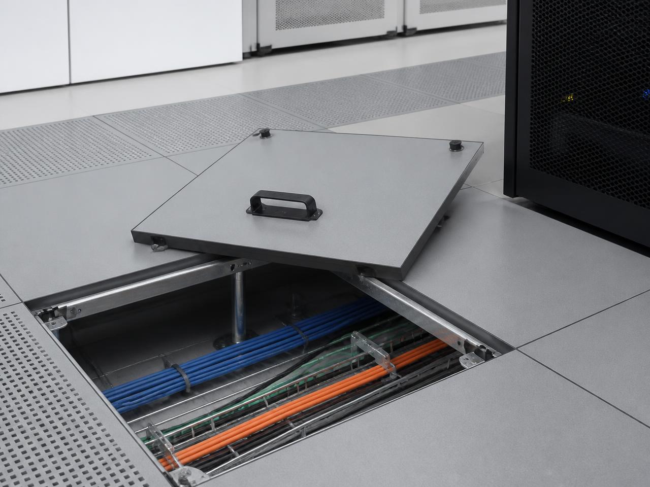 Raised access floor panel lifted to show the subfloor cable pathways beneath